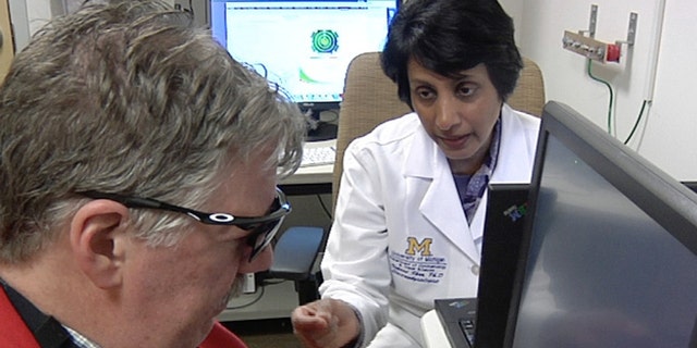 In this April 16, 2014 image from video Dr. Naheed Khan, right, works with Roger Pontz, left, on an exercise to test how well he sees shapes on a computer screen at the University of Michigan Kellogg Eye Center, April 16, 2014, in Ann Arbor, Mich. Pontz suffers from a degenerative eye disease called retinitis pigmentosa and is the second patient in the U.S. to surgically receive a bionic eye since the U.S. Food and Drug Administration signed off on its use last year. (AP Photo, Mike Householder)