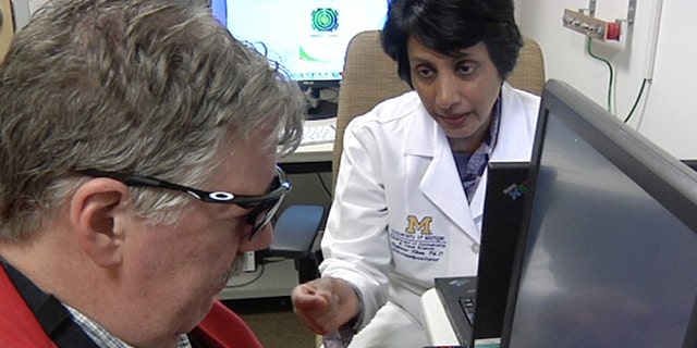 In this April 16, 2014 image from video Dr. Naheed Khan, right, works with Roger Pontz, left, on an exercise to test how well he sees shapes on a computer screen at the University of Michigan Kellogg Eye Center, April 16, 2014, in Ann Arbor, Mich. Pontz suffers from a degenerative eye disease called retinitis pigmentosa and is the second patient in the U.S. to surgically receive a bionic eye since the U.S. Food and Drug Administration signed off on its use last year. (AP Photo, Mike Householder)