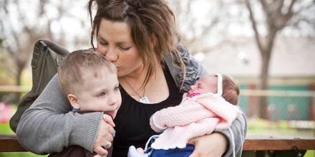 Rachel Rabey and her children sit in Ann Morrison Park in Boise, Id. While in labor in 2010, Rabey let paramedics drive past two nearby hospitals to a third facility in Boise, adding minutes to a journey that ended in the death of her newborn child. (AP Photo/The Idaho Statesman, Chris Butler)