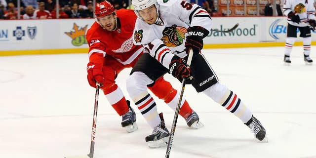 Detroit Red Wings left wing Drew Miller (20) defends Chicago Blackhawks defenseman Trevor van Riemsdyk (57) in the first period of an NHL hockey game in Detroit, Friday, Nov. 14, 2014. (AP Photo/Paul Sancya)