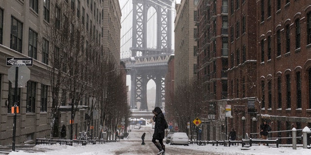 The Manhattan Bridge is seen in the background as commuters make their way through the streets of Dumbo after a snow storm in New York Jan. 27, 2015.