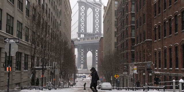 The Manhattan Bridge is seen in the background as commuters make their way through the streets of Dumbo after a snow storm in New York Jan. 27, 2015.