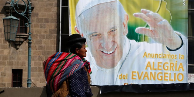 An Aymara indigenous woman walks past a billboard featuring Pope Francis with a message that reads in Spanish: "Announcing the joy of the Gospel" in La Paz, Bolivia, Friday, July 3, 2015. The pope's trip to South America that includes Bolivia is set for July 5-12, though he will only spend four hours in Bolivia's capital due to the altitude, church officials say. (AP Photo/Juan Karita)