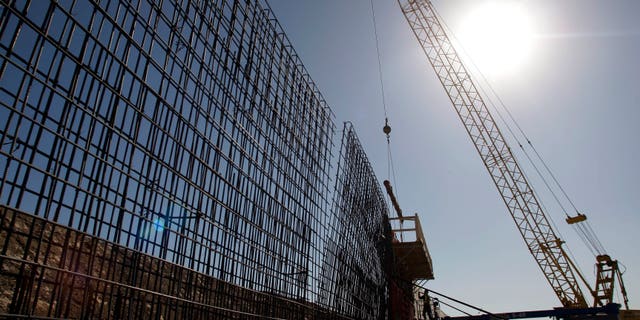 File - In this Feb. 4, 2009 file photo, the sun beats down on construction workers constructing the border wall in Granjeno, Texas. If Congress agrees on a comprehensive immigration reform bill, it will probably include a requirement to erect fencing that would wrap more of the nation's nearly 2,000-mile Southwest border in tall steel columns. But the mandate would essentially double down on a strategy that the Customs and Border Protection agency isn't even sure works. (AP Photo/Eric Gay, File)