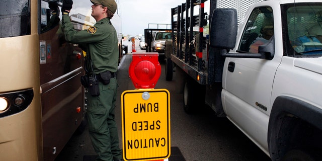 FILE - This July 29, 2010 file photo shows a Border Patrol agent checking the identification card of a bus driver at a checkpoint in Amado, Ariz. The American Civil Liberties Union reported Wednesday Jan. 15, 2014 that border patrol agents at checkpoints across southern Arizona are routinely violating the constitutional rights of U.S. residents, including unjustified detentions and illegal searches as a pretext to investigating other criminal activity in violation of the agency's mandate that stops be limited to inquiring about citizenship and visually inspecting vehicles. (AP Photo/Jae C. Hong, file)