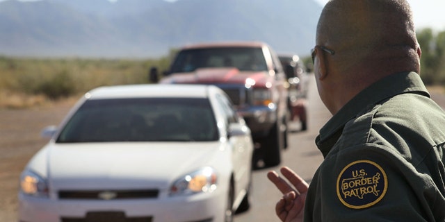 A Border Patrol agent checks vehicles for illegal immigrants and contraband at a roadside checkpoint June 1, 2010 near Sasabe, Arizona. (Photo by Scott Olson/Getty Images)