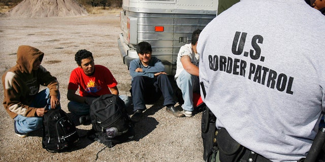 FILE - In this Jan. 19, 2007 file photo, the U.S. Border Patrol detains a large group of suspected immigrants at the Arizona-Mexico border in Sasabe, Ariz. A federal judge has barred use of a policy that allowed people who paid to be sneaked into the United States to be charged under Arizonaâs immigrant smuggling law as conspirators to the crime. U.S. District Judge Robert Broomfieldâs ruling said the interpretation of the 2005 state law conflicts with federal law. The ruling is the latest in a series of restrictions placed on Maricopa County Sheriff Joe Arpaioâs immigration enforcement efforts. (AP Photo/Ross D. Franklin, File)