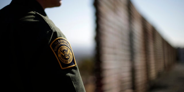 In this June 13, 2013 picture, U.S. Border Patrol agent Jerry Conlin looks to the north near where the border wall ends as is separates Tijuana, Mexico, left, and San Diego, right.  Illegal immigration into the United States would decrease by only 25 percent under a far-reaching Senate immigration bill, according to an analysis by the Congressional Budget Office that also finds the measure reduces federal deficits by billions. (AP Photo/Gregory Bull)