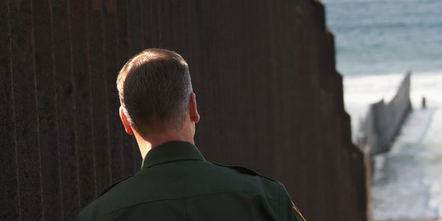 SAN DIEGO, CA - OCTOBER 03: A U.S. Border Patrol agent looks to where the U.S.-Mexico border fence stretches into the Pacific Ocean on October 3, 2013 in San Diego, California. While hundreds of thousands of government workers were furloughed this week, thousands of Border Patrol agents, air-traffic controllers, prison guards and other federal employees deemed "essential" remain on duty, although their pay may be delayed. (Photo by John Moore/Getty Images)