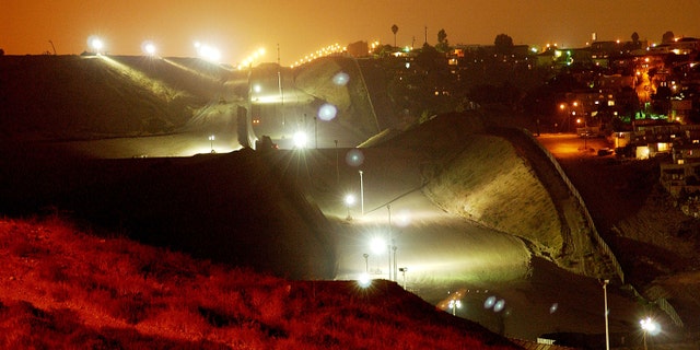 394677 03: Lights, fences, and barren land create an erie no man's land between the Tijuana, Mexico neighborhood of Colonia Libertad (R) and the U.S., September 19, 2001 east of San Ysidro, CA. Operation Gatekeeper's border crackdown of recent years has created the prison-like appearance and has made the border easier to defend against possible terrorist crossings. (Photo by David McNew/Getty Images)