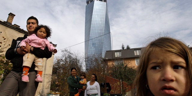 Nov. 12: A Roma family are seen outside their temporary accommodation, backdropped by the largest office block in central Sarajevo, Bosnia.