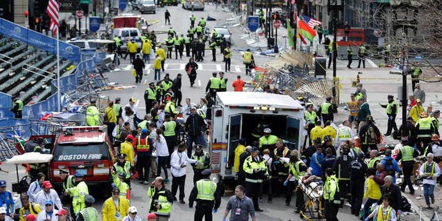 ARCHIVO - En esta foto de archivo del 15 de abril de 2013, los trabajadores médicos ayudan a las personas heridas en la línea de meta del maratón de Boston de 2013 luego de una explosión en Boston.  La selección del jurado para el juicio del sospechoso de atentado con bomba Dzhokhar Tsarnaev está programada para comenzar el lunes 5 de enero de 2015 en un tribunal federal de Boston.  (Foto AP/Charles Krupa, archivo)