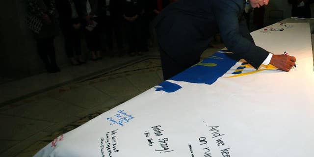 Mass. Gov. Deval Patrick signs the America 4 Prayer Canvas in support and remembrance of the 2013 Boston Marathon bombing victims and survivors at the Statehouse in Boston, Friday, April 11, 2014. (AP Photo/Elise Amendola)
