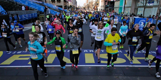 At the midpoint of the 5K race, runners cross the finish line of the Boston Marathon, Saturday, April 19, 2014, in Boston.