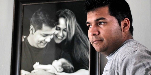 FILE - In this Friday, Jan. 3, 2014 file photo, Erick Munoz stands with an undated copy of a photograph of himself, left, with wife Marlise and their son Mateo, in Haltom City, Texas. Munozâs attorneys said in a statement Wednesday, Jan. 22, 2014, that the fetus that Marlise Munoz is carrying has several âabnormalities,â including a deformation of the lower body parts that make it impossible to determine its gender. (AP Photo/The Fort Worth Star-Telegram, Ron T. Ennis, File)