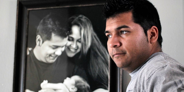 FILE - In this Friday, Jan. 3, 2014 file photo, Erick Munoz stands with an undated copy of a photograph of himself, left, with wife Marlise and their son Mateo, in Haltom City, Texas. Munozâs attorneys said in a statement Wednesday, Jan. 22, 2014, that the fetus that Marlise Munoz is carrying has several âabnormalities,â including a deformation of the lower body parts that make it impossible to determine its gender. (AP Photo/The Fort Worth Star-Telegram, Ron T. Ennis, File)
