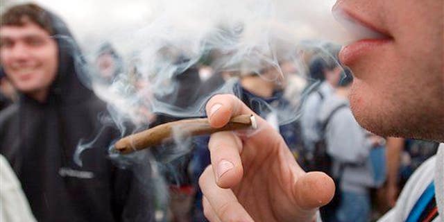 In an April 20, 2005, file photo, a University of Colorado freshman who did not want to be identified joins a crowd smoking marijuana during a "420" gathering at the University of Colorado in Boulder.