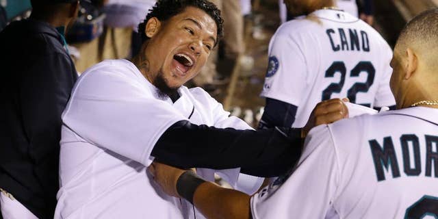 Seattle Mariners starting pitcher Felix Hernandez, left, lets out a yell and playfully grabs teammate Kendrys Morales' jersey after coming out of the baseball game after throwing eight innings against the Atlanta Braves on Tuesday, Aug. 5, 2014, in Seattle. (AP Photo/Elaine Thompson)