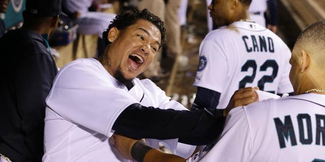 Seattle Mariners starting pitcher Felix Hernandez, left, lets out a yell and playfully grabs teammate Kendrys Morales' jersey after coming out of the baseball game after throwing eight innings against the Atlanta Braves on Tuesday, Aug. 5, 2014, in Seattle. (AP Photo/Elaine Thompson)