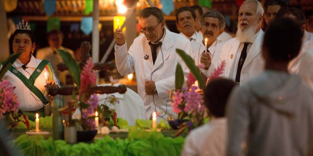 In this June 22, 2016 photo, Godfather Alfredo Gregorio, center, leads a religious service in the church of doctrine of the Holy Daime, in Ceu do Mapia, Amazonas state, Brazil. Alfredo Gregorio de Melo is son of the village founder, rubber tapper Sebastiao Mota de Melo, nicknamed Godfather Sebastiao. (AP Photo/Eraldo Peres)