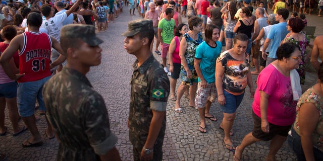 In this Nov. 21, 2015 photo, residents stand in line at a free water distribution site, weeks after a dam burst at the Samarco iron mine, causing mudslides and contaminated the area's drinkable water supplies, in Colatina, Brazil. The bottled water is provided by Samarco, which is jointly owned by mining giants Vale of Brazil and Australiaâs BHP Billiton. (AP Photo/Leo Correa)