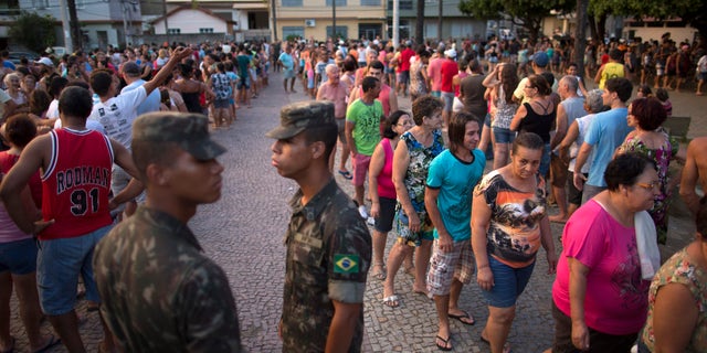 In this Nov. 21, 2015 photo, residents stand in line at a free water distribution site, weeks after a dam burst at the Samarco iron mine, causing mudslides and contaminated the area's drinkable water supplies, in Colatina, Brazil. The bottled water is provided by Samarco, which is jointly owned by mining giants Vale of Brazil and Australiaâs BHP Billiton. (AP Photo/Leo Correa)