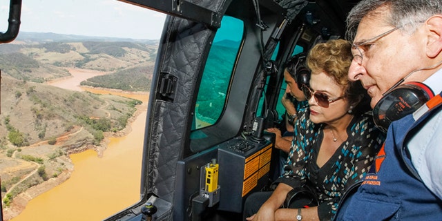 In this photo released by the official web site of the Brazilian Presidency, President Dilma Rousseff accompanied by Minas Gerais state Gov. Fernando Pimentel, looks out over the area of dam bursts at an iron ore mine, in the southeastern Brazilian state of Minas Gerais, Thursday, Nov. 12, 2015. Last week dam failures unleashed a deadly wave of viscous mud that all but erased a hamlet and contaminated a key river. Rousseff says the mining company, Samarco, will be made to pay for the cleanup. (Roberto Stuckert Filho/Brazil Presidential Press Office via AP)