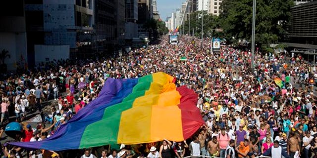 Participants carry a rainbow flag as thousands march during the annual Gay Pride Parade in Sao Paulo, Brazil, Sunday, May 4, 2014. Gay rights advocates are calling for a Brazilian law against discrimination as they gather by the hundreds of thousands in Sao Paulo for one of the world's largest gay pride parades. (AP Photo/Andre Penner)