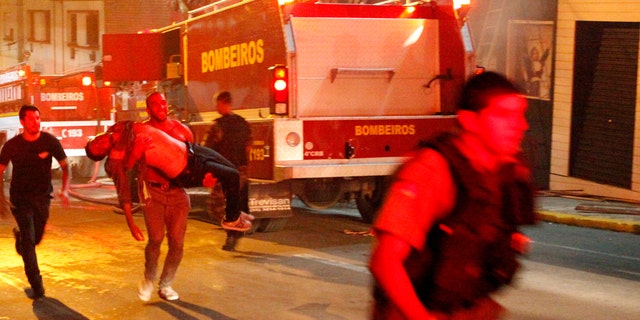 A man carries an injured man, victim of a fire at the Kiss  club in Santa Maria city,  Rio Grande do Sul state, Brazil, early Sunday, Jan. 27, 2013.  (AP Photo/Agencia RBS)