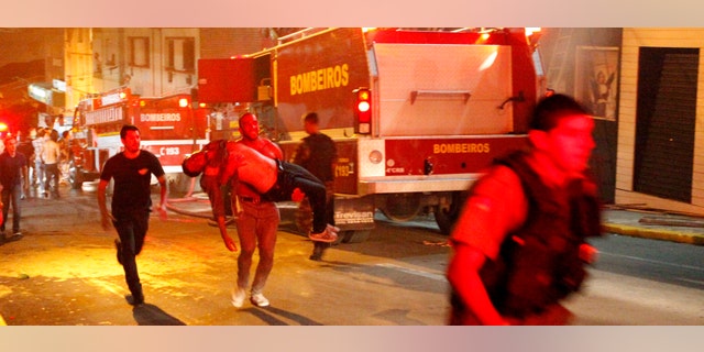A man carries an injured man, victim of a fire at the Kiss club in Santa Maria city, Rio Grande do Sul state, Brazil, early Sunday, Jan. 27, 2013. (AP Photo/Agencia RBS)