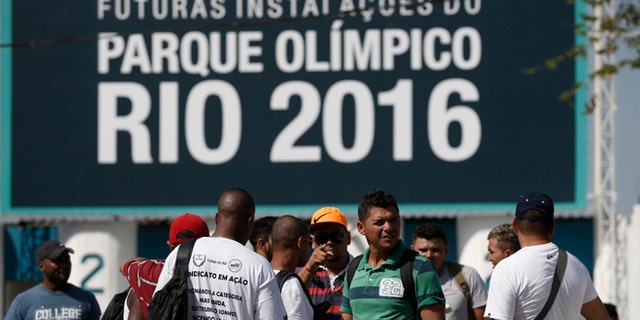 Striking workers stand in front the entrance of the Olympic Park, the main cluster of venues under construction for the 2016 Summer Olympic Games, in Rio de Janeiro, Brazil, Tuesday, April 8, 2014. The labor dispute centers around which union represents the construction workers, and also involves benefits and working conditions. (AP Photo/Silvia Izquierdo)