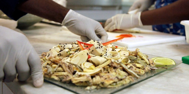 In this May 6, 2016 photo, cooks prepare meals during the food-testing of the Olympic menu in Rio de Janeiro, Brazil. Diners will choose from five different buffets: Brazilian, Asian, International, Pasta and Pizza, Halal and Kosher. (AP Photo/Renato Spyrro)