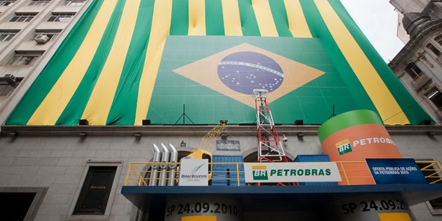 FILE - In this Sept. 24, 2010 file photo, a Brazilian flag and the word "Petrobras" decorate the entrance of the stock market building on the first day of trading in Sao Paulo, Brazil. Brazils Attorney General Rodrigo asked the nations Supreme Court on Tuesday, March 3, 2015 for permission to investigate top political figures for alleged involvement in a kickback scheme at the state-run oil company Petrobras, which prosecutors say is the countrys largest corruption scandal yet uncovered. (AP Photo/Andre Penner, File)
