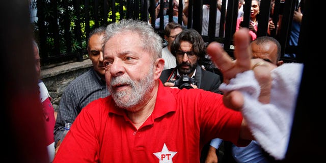 FILE - In this March 5, 2016 file photo, Brazil's former President Luiz Inacio Lula da Silva greets supporters who gathered outside his residence in Sao Bernardo do Campo, in the greater Sao Paulo area, Brazil. A Brazilian judge has ruled that Silva will stand trial on charges of money laundering and corruption. Judge Sergio Moro said Tuesday, Sept. 20, 2016 there is enough evidence to start a judicial process against Silva, his wife and six others in a widening corruption probe centered on the country's huge state-run oil company, Petrobras. (AP Photo/Andre Penner, File)