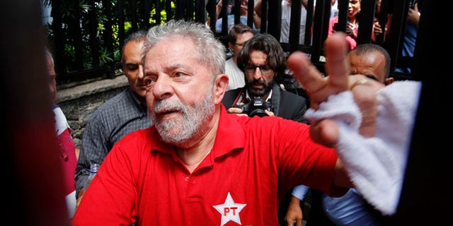 FILE - In this March 5, 2016 file photo, Brazil's former President Luiz Inacio Lula da Silva greets supporters who gathered outside his residence in Sao Bernardo do Campo, in the greater Sao Paulo area, Brazil. A Brazilian judge has ruled that Silva will stand trial on charges of money laundering and corruption. Judge Sergio Moro said Tuesday, Sept. 20, 2016 there is enough evidence to start a judicial process against Silva, his wife and six others in a widening corruption probe centered on the country's huge state-run oil company, Petrobras. (AP Photo/Andre Penner, File)