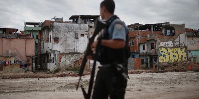 RIO DE JANEIRO, BRAZIL - MAY 27: A police officer patrols past an area where homes were torn down in the Manguinhos community on May 27, 2014 in Rio de Janiero, Brazil. Residents from one section of the 'favela', visited by Pope Francis in July 2013, have been affected by construction from the improvement works project begun in 2008. A full sanitation system has yet to be built. Evictions and demolitions have been occurring in Rio favelas ahead of the 2014 FIFA World Cup and Rio 2016 Olympic Games in spite of a housing shortage in the city. Rio's housing and urban planning goals include a planned five percent reduction of areas occupied by favelas by 2016. Alternative affordable housing, generally on the peripheries of the city, is unable to meet demand and some residents complain they have not received adequate compensation for demolished homes. (Photo by Mario Tama/Getty Images)