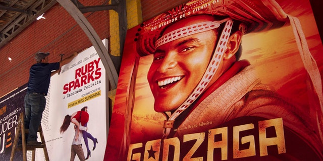 A worker hangs a poster promoting the Brazilian film "Gonzaga - from Father to Son" in Rio de Janeiro, Brazil, Friday, Sept. 28, 2012. The Rio de Janeiro International Film Festival is flooding this metropolis with hundreds of movies. The festival that launched late Thursday is Latin America's largest in terms of sheer volume, with feature films, documentaries, shorts and children's movies from more than 60 countries. (AP Photo/Silvia Izquierdo)