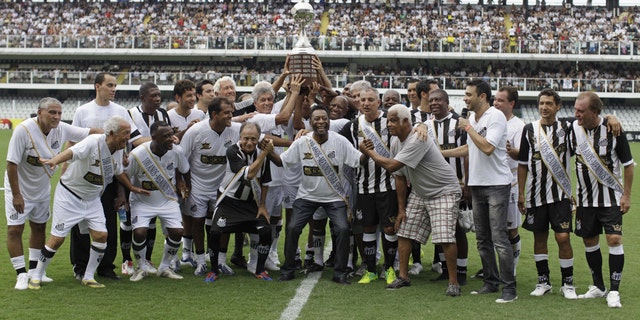Pelé, center, with other former Santos soccer players hold up the Libertadores championship trophy during during the centennial anniversary celebration of the team in Santos, Brazil, Saturday, April 14, 2012. Santos, the Brazilian club that ruled football with "The King," Pele in the 1960s, turned 100 with a rich history to show, including many major titles and remarkable victories that have made the club one of the most successful in football. (AP Photo/Nelson Antoine)