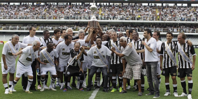 Pelé, center, with other former Santos soccer players hold up the Libertadores championship trophy during during the centennial anniversary celebration of the team in Santos, Brazil, Saturday, April 14, 2012. Santos, the Brazilian club that ruled football with "The King," Pele in the 1960s, turned 100 with a rich history to show, including many major titles and remarkable victories that have made the club one of the most successful in football. (AP Photo/Nelson Antoine)