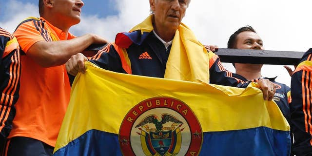 FILE - In this July 6, 2014 file photo, Colombia's coach Jose Pekerman, from Argentina, holds a Colombian flag as the team parades before supporters as they are welcomed home from the World Cup, in Bogota, Colombia, following their loss to Brazil in the quarterfinals. Colombia's Football Federation announced on Tuesday, Aug. 19, 2014 that Pekerman will stay on as coach for the national selection. (AP Photo/Fernando Vergara, File)