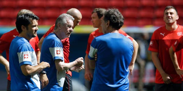Switzerland's coach Ottmar Hitzfeld, second left, talks to staff members and players during an official training session the day before the group E World Cup soccer match between Switzerland and Ecuador at the Estadio Nacional in Brasilia, Brazil, Saturday, June 14, 2014.  (AP Photo/Michael Sohn)