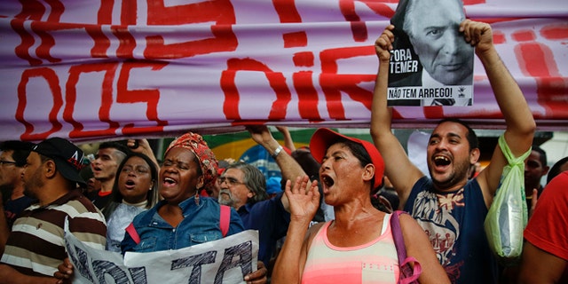 With signs that read in Portuguese "Dilma come back" and "Temer Out," demonstrators shout slogans during a protest against Brazil's acting President Michel Temer and in support of Brazil's suspended President Dilma Rousseff, close to Temer's residence in São Paulo, Brazil, Sunday, May 22, 2016. Temer took office after Rousseff was suspended for up to 180 days while the Senate holds an impeachment trial. (AP Photo/Andre Penner)