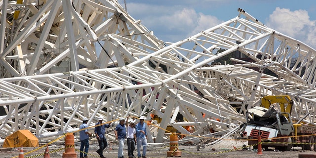 Civil defense and policemen inspect the damage of an accident at the Arena Corinthians, known locally as the Itaquerao, that will host the 2014 World Cup in Sao Paulo, Brazil, Thursday, Nov. 28, 2013. Two workers were killed when a crane crashed into a 500-ton metal structure that toppled over part of the stadium Wednesday, aggravating already urgent worries that Brazil won't be ready for soccer's showcase event next year. (AP Photo/Andre Penner)