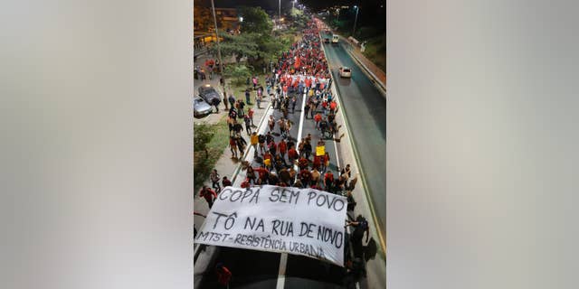 Members of the Homeless Workers Movement holding a banner that reads in Portuguese "World Cup without the People, then I am in the street again", march during a protest demanding better public services and against the money spent on the World Cup preparations in Sao Paulo, Brazil, Wednesday, June 4, 2014. (AP Photo/Nelson Antoine)