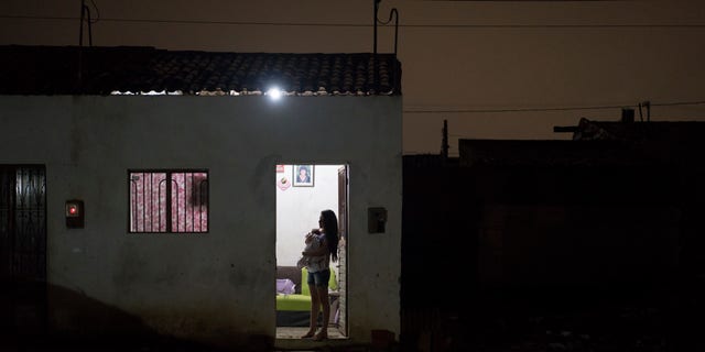 In this Dec. 22, 2015 photo, Angelica Pereira holds her daughter Luiza as she waits for her husband at their house in Santa Cruz do Capibaribe, Pernambuco state, Brazil. In the early weeks of Angelica Pereiras pregnancy, a mosquito bite began bothering her. At first it seemed a small thing. But the next day she awoke with a rash all over her body, a headache, a fever and a burning in her eyes. The symptoms disappeared within four days, but she fears the virus has left lasting consequences. (AP Photo/Felipe Dana)