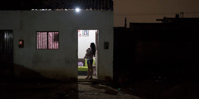 In this Dec. 22, 2015 photo, Angelica Pereira holds her daughter Luiza as she waits for her husband at their house in Santa Cruz do Capibaribe, Pernambuco state, Brazil. In the early weeks of Angelica Pereiras pregnancy, a mosquito bite began bothering her. At first it seemed a small thing. But the next day she awoke with a rash all over her body, a headache, a fever and a burning in her eyes. The symptoms disappeared within four days, but she fears the virus has left lasting consequences. (AP Photo/Felipe Dana)