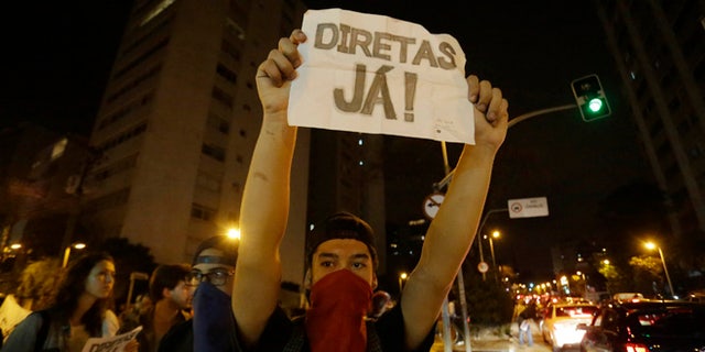 A man holds a sign that reads "Elections now" during a protest against President Michel Temer in Sao Paulo, Brazil, Sunday, Sept. 4, 2016. Temer was sworn in as Brazil's new leader on Wednesday following the ouster of President Dilma Rousseff. (AP Photo/Nelson Antoine)
