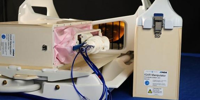 The Image-Guided Autonomous Robot, or IGAR, aims to make breast biopsies more precise and automated. Here, the IGAR manipulator and full breast intervention platform are mounted on the patient support structure with a biopsy tool attached.