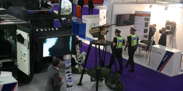 Police walk past a French Panhard armored personnel vehicle, with police markings to underscore its use beyond traditional battle fields as the Defence & Security Equipment International show gets underway in London, Tuesday Sept. 13, 2011.