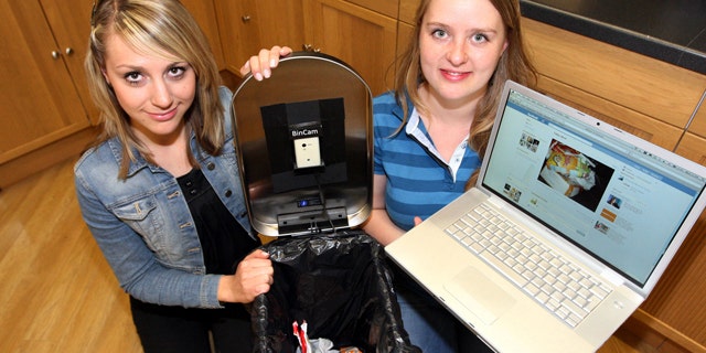 June 8, 2011: Newcastle University students Julia Miebach, left, and Anja Thieme, right, with the Bincam and a laptop showing its Facebook page. Five households have signed up for a program announced Wednesday that puts photographs of every item placed in a garbage can on Facebook, to raise consciousness about recycling efforts.